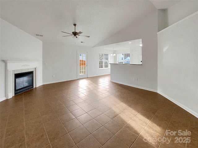 unfurnished living room featuring dark tile patterned floors, ceiling fan, lofted ceiling, and a fireplace