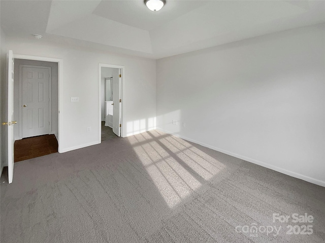 unfurnished bedroom featuring a raised ceiling and dark colored carpet