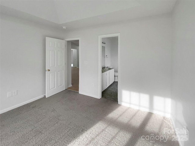 unfurnished bedroom with sink, connected bathroom, and dark carpet