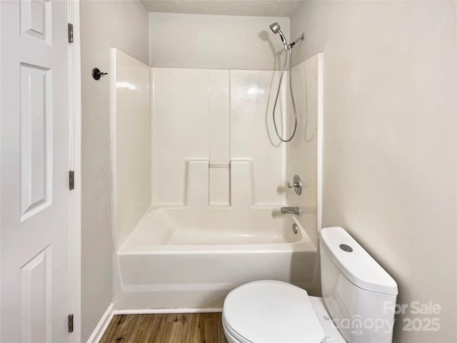 bathroom with hardwood / wood-style floors, a textured ceiling,  shower combination, and toilet