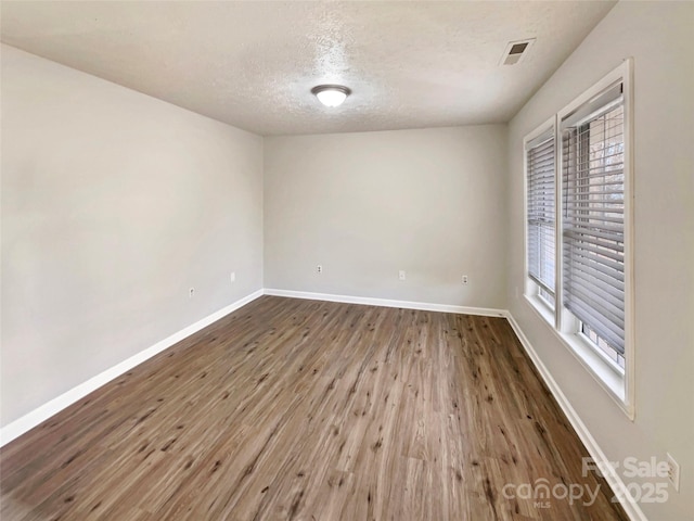 unfurnished room with wood-type flooring and a textured ceiling