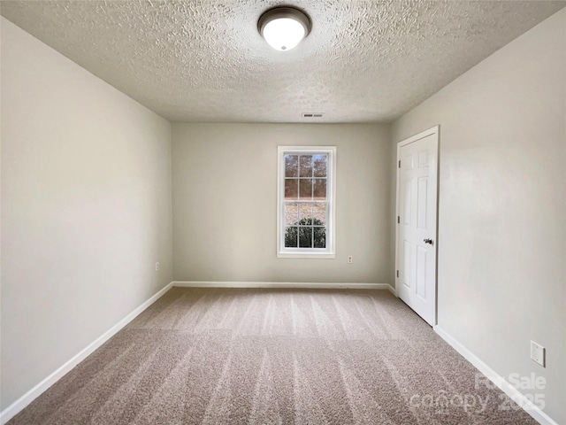 carpeted empty room with a textured ceiling