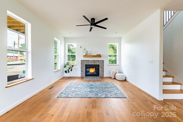 unfurnished living room with a tiled fireplace, plenty of natural light, and light hardwood / wood-style flooring