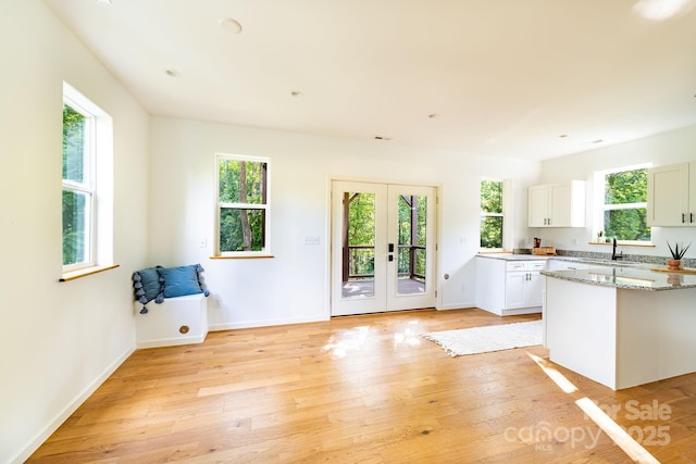 kitchen with french doors, sink, light stone counters, light hardwood / wood-style flooring, and white cabinets