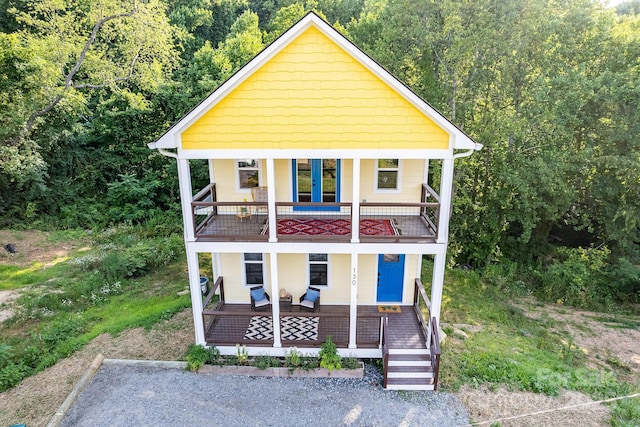 view of front of home with french doors, a balcony, and covered porch