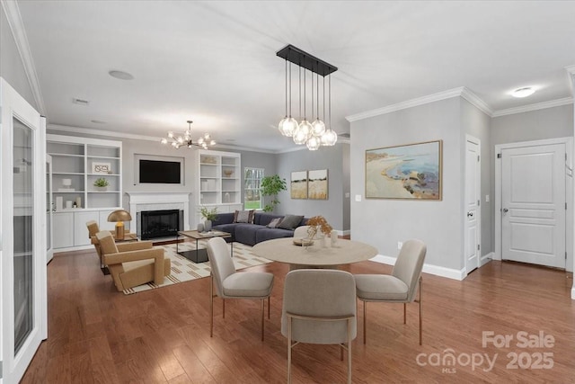 dining room featuring crown molding, hardwood / wood-style floors, built in features, and a notable chandelier