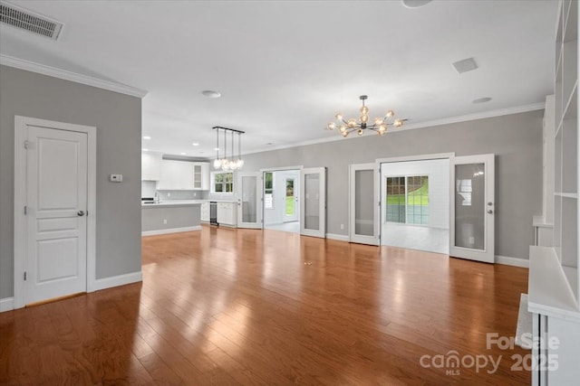 unfurnished living room with plenty of natural light, ornamental molding, and a chandelier