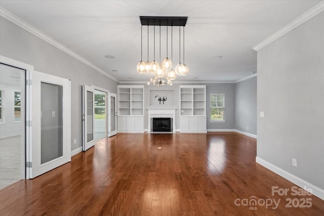 unfurnished living room with crown molding, dark hardwood / wood-style floors, built in features, and a notable chandelier