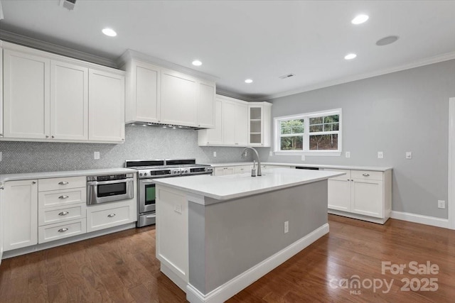 kitchen featuring stainless steel range, dark hardwood / wood-style floors, white cabinets, and a center island with sink