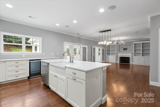 kitchen with sink, white cabinetry, a center island with sink, built in shelves, and stainless steel dishwasher