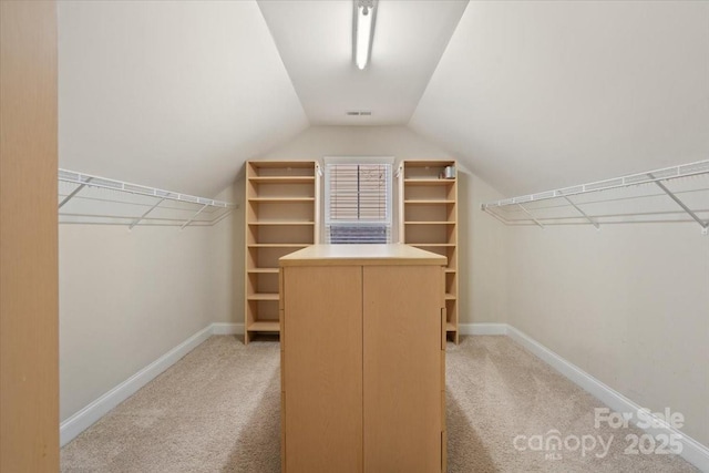 walk in closet with lofted ceiling and light colored carpet