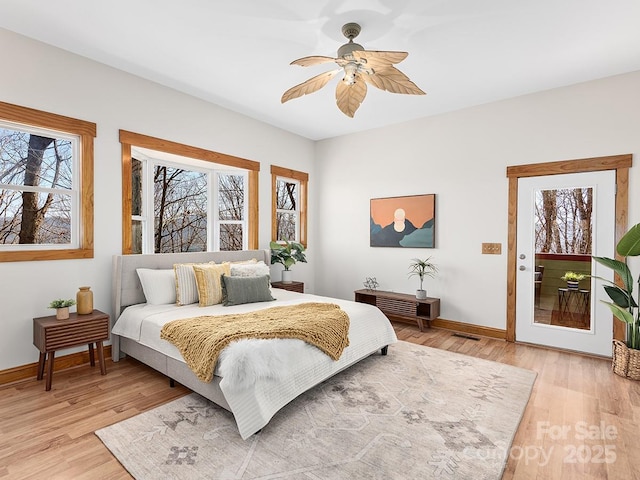 bedroom with light wood finished floors, multiple windows, and baseboards