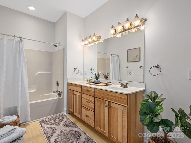 full bathroom with double vanity, shower / tub combo, a sink, and wood finished floors