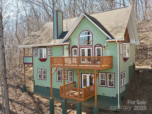 exterior space with a shingled roof, a chimney, and a wooden deck