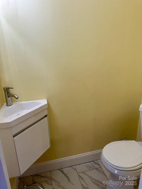 bathroom with marble finish floor, toilet, vanity, and baseboards