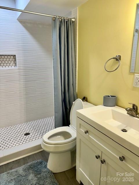 full bathroom featuring vanity, a shower stall, toilet, and wood finished floors