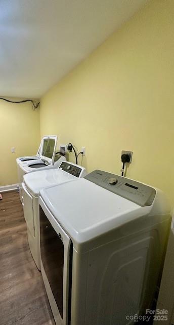 washroom with dark wood-type flooring, washing machine and dryer, baseboards, and laundry area