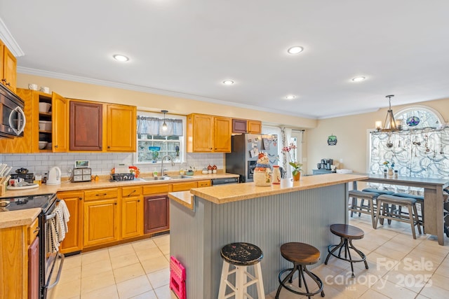 kitchen with pendant lighting, sink, a breakfast bar area, appliances with stainless steel finishes, and a center island