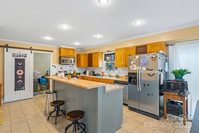 kitchen featuring light tile patterned flooring, a breakfast bar area, stainless steel appliances, crown molding, and a barn door