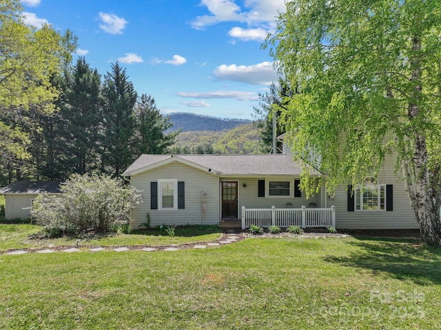 ranch-style home featuring a front lawn, a mountain view, a porch, and roof with shingles