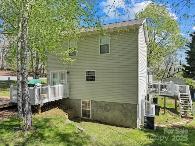back of house with central AC, a deck, stairs, and a lawn
