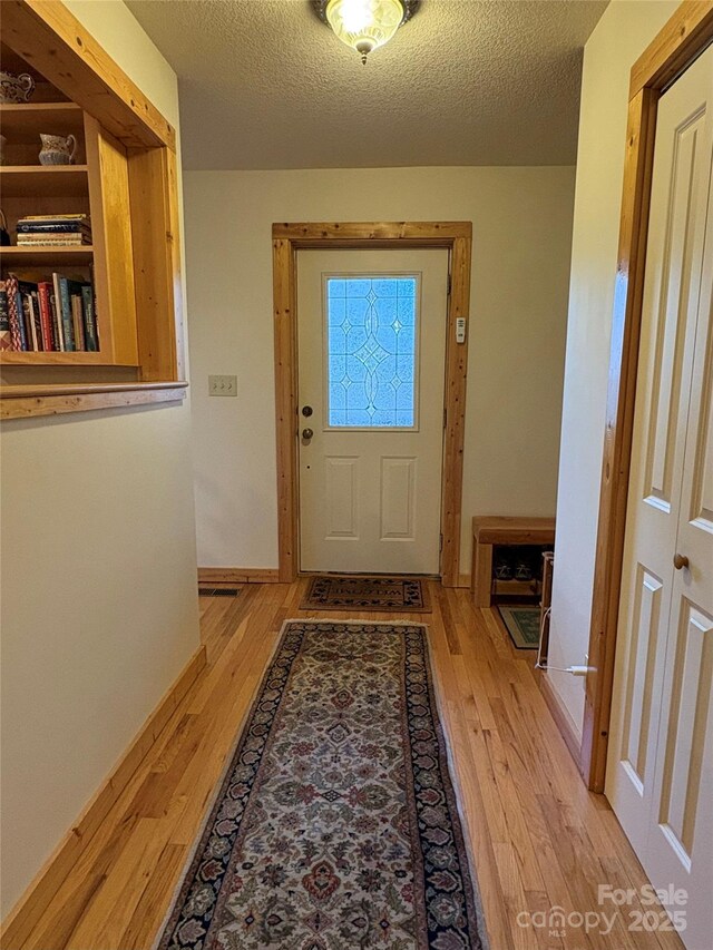 entryway with a textured ceiling and light wood-type flooring