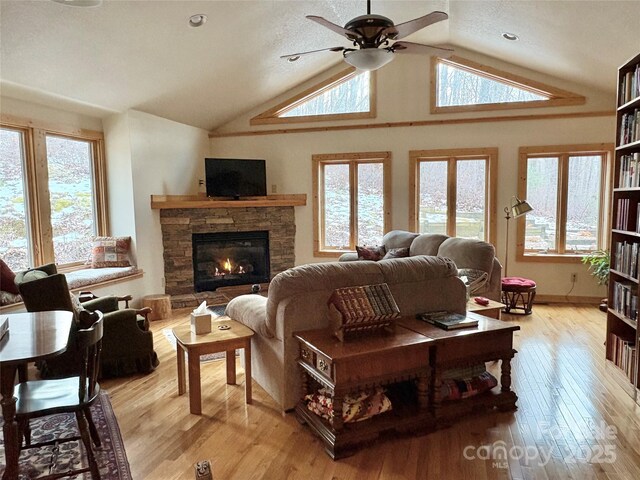 living room with a fireplace, vaulted ceiling, light hardwood / wood-style floors, and ceiling fan