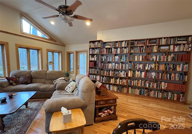 living room with hardwood / wood-style flooring, ceiling fan, and high vaulted ceiling