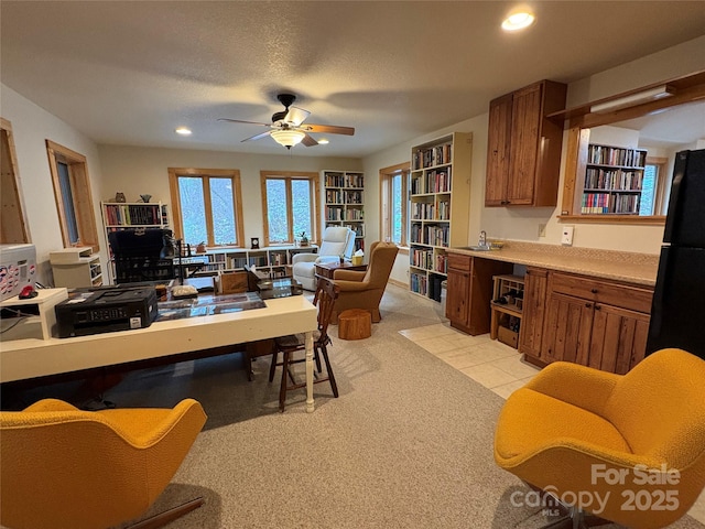 interior space with light colored carpet, a textured ceiling, and ceiling fan