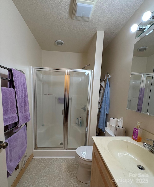 bathroom featuring vanity, a textured ceiling, toilet, and walk in shower