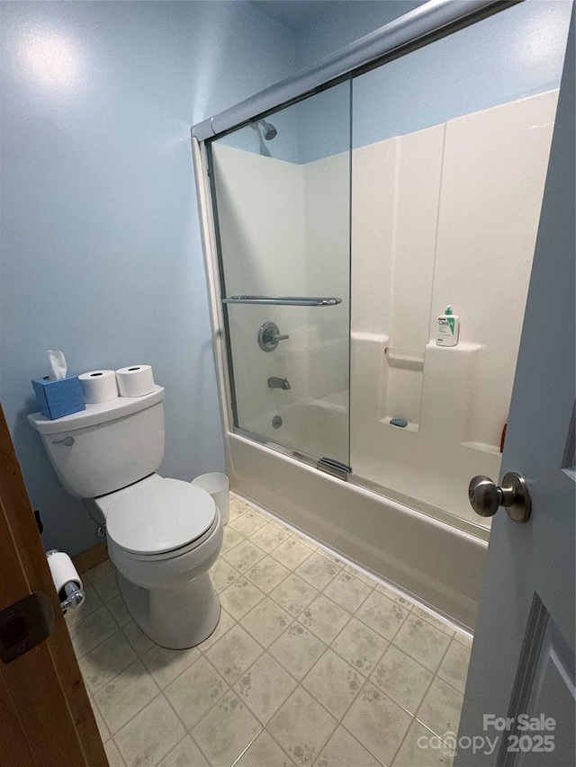 bathroom featuring toilet and shower / bath combination with glass door