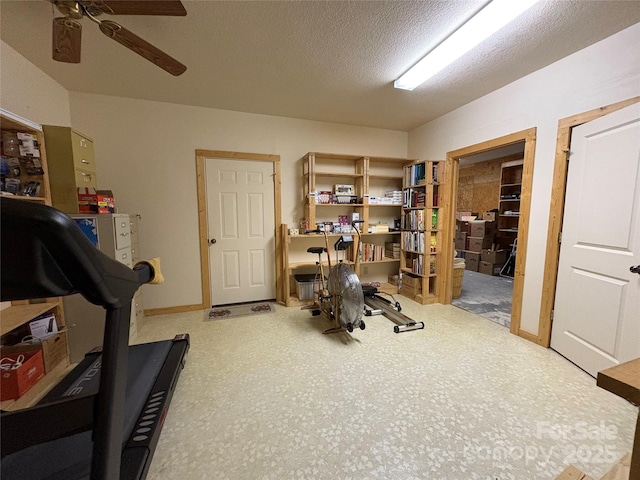 exercise room with ceiling fan and a textured ceiling