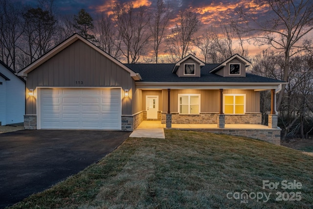 view of front of house featuring a garage, covered porch, and a lawn