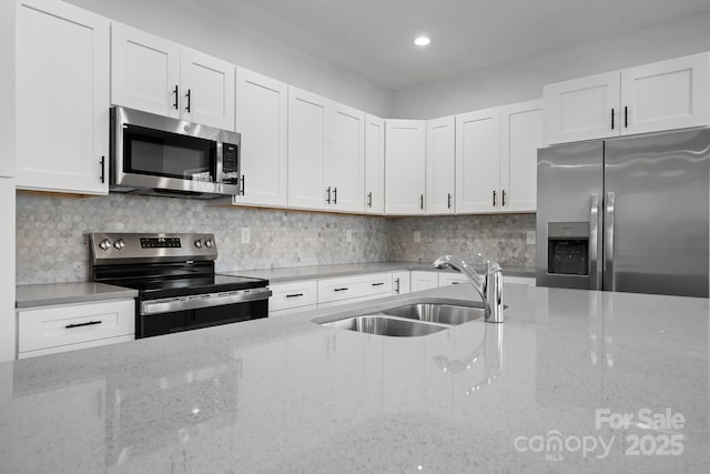 kitchen featuring light stone counters, sink, white cabinets, and appliances with stainless steel finishes