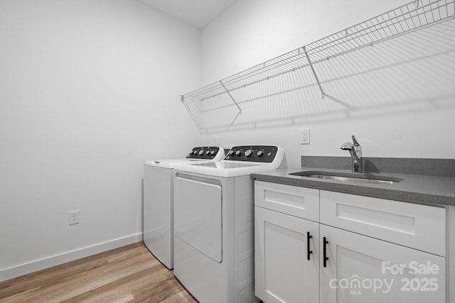 washroom with washer and dryer, sink, cabinets, and light hardwood / wood-style floors