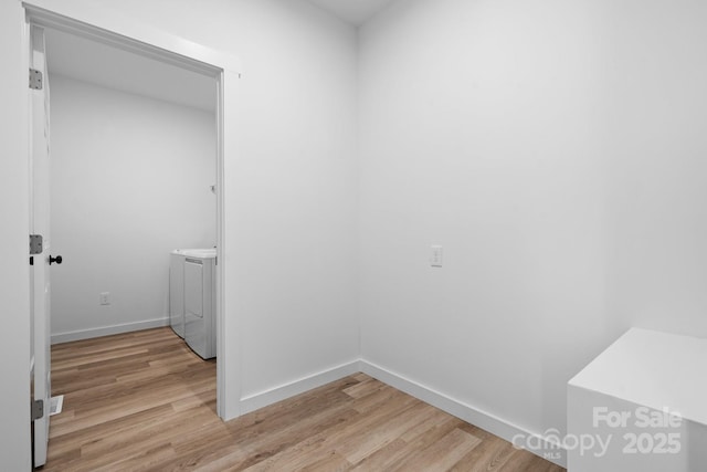 laundry room with washer and clothes dryer and light hardwood / wood-style flooring