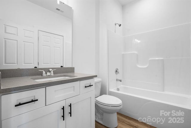 full bathroom featuring vanity, hardwood / wood-style flooring, tub / shower combination, and toilet