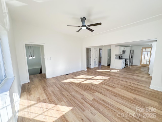 unfurnished living room with a ceiling fan, baseboards, and light wood finished floors