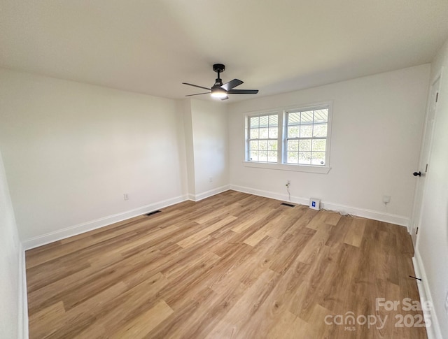 spare room featuring visible vents, baseboards, light wood finished floors, and ceiling fan