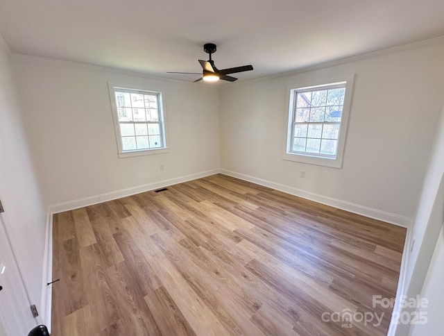 empty room with baseboards, ornamental molding, visible vents, and light wood finished floors