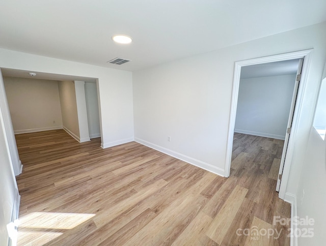 unfurnished room featuring baseboards, light wood-style floors, and visible vents