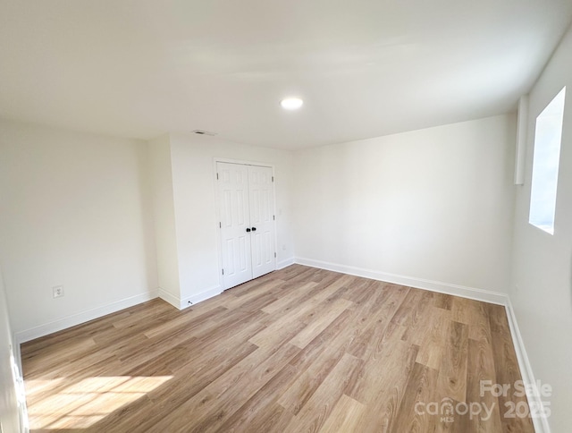 empty room with baseboards, visible vents, and light wood-type flooring