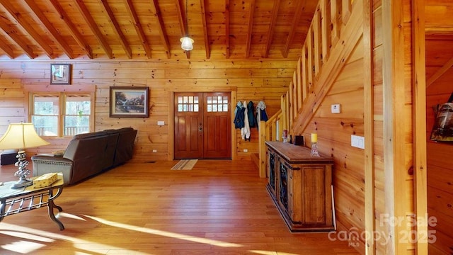 entryway with beamed ceiling, wood-type flooring, and wooden walls