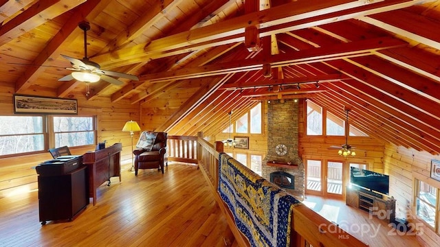 interior space featuring vaulted ceiling with beams, hardwood / wood-style flooring, ceiling fan, and wood walls