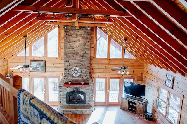 unfurnished living room featuring hardwood / wood-style flooring, wooden walls, plenty of natural light, and a fireplace