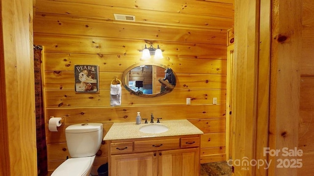 bathroom with wooden walls, vanity, and toilet