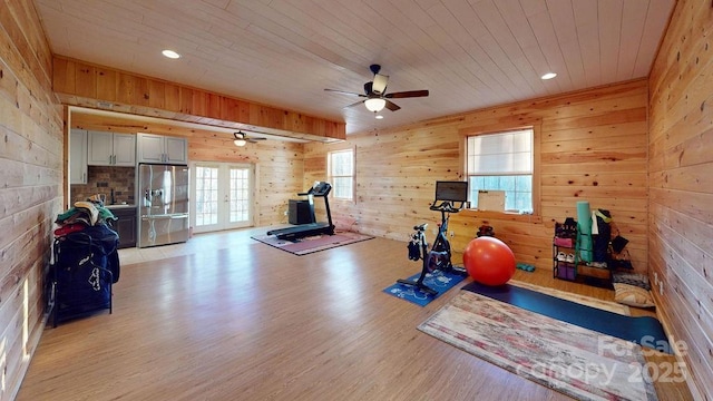 exercise room featuring french doors, wood walls, wooden ceiling, and light wood-type flooring