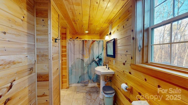 bathroom featuring wood ceiling, wooden walls, and a shower with curtain