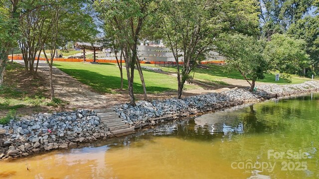 view of home's community with a water view and a lawn