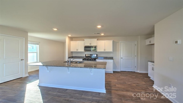 kitchen featuring appliances with stainless steel finishes, a kitchen island with sink, sink, and a kitchen breakfast bar